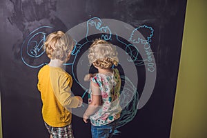 Boy and girl paint with chalk on a blackboard