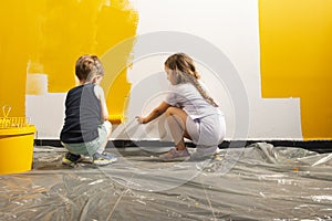 A boy and a girl paints a wall at home in yellow