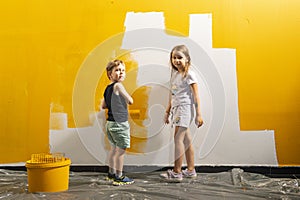 A boy and a girl paints a wall at home in yellow