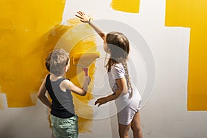 A boy and a girl paints a wall at home in yellow