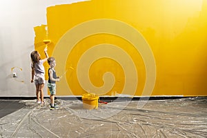 A boy and a girl paints a wall at home in yellow