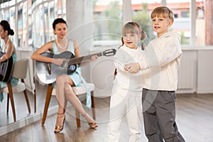 Boy and girl in pair train to dance tango during classes with accompaniment of guitar