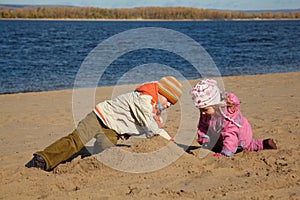 Boy and girl play sand on beach on river bank