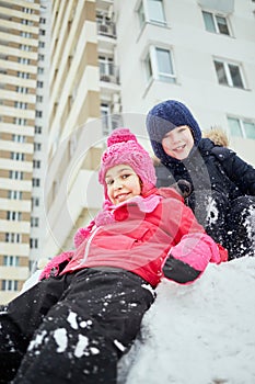Boy and girl play in snow at courtyard near photo