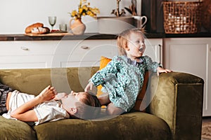 Boy and girl play on the sofa in the children`s bedroom. Brother and sister happily spend time together