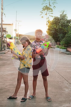 Boy and girl play water gun together on Songkran festival in Thai