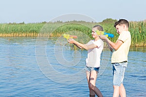 Boy and girl play with water pistols on the river