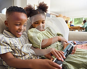 Boy And Girl Playing With Handheld Gaming Device At Home With Multi-Generation Family In Background photo