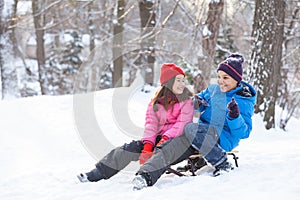 Boy and girl playing outside on sledges.