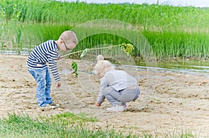 Boy and girl playing in the sand on shore of Lake