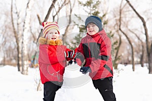 Boy and girl playing with snow in winter park