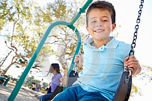 Boy And Girl Playing On Swing In Park