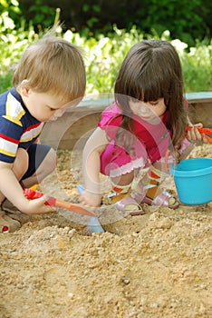 The boy and girl playing to a sandbox