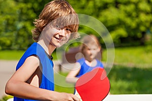 Boy and girl playing together ping pong outside