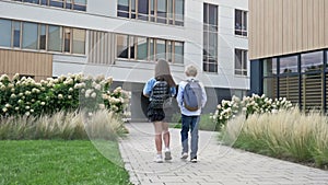 A boy and a girl, primary school students, are walking around the school yard and talking about something. School