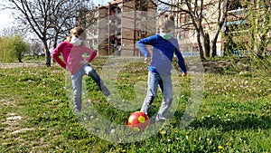 A boy and a girl in protective surgical masks play a ball and dance on the green grass. Protection against airborne diseases. The