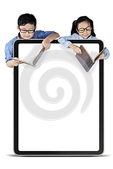 Boy and girl reading book behind whiteboard