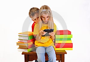 Boy and girl reading e-book surrounded by books