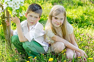 A boy and a girl are resting in a blooming garden in the spring
