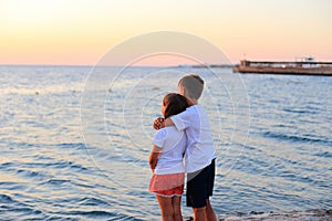 A boy and a girl are resting on the sea at dawn.