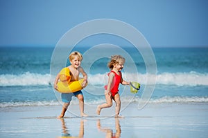 Boy with girl run holding inflatable buoys duck and toy at beach