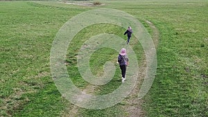 A boy and a girl are running around the field.