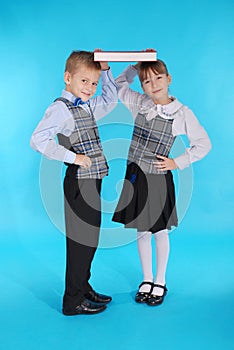 Boy and girl in school uniform holding a book on her head