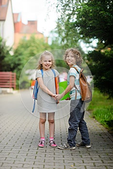 Boy and girl with schoolbags hold hands.