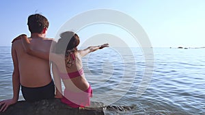 Boy and girl on the sea. A boy and girl are sitting on the rocks on the sea view from the back of a romance happy