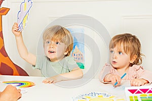 Boy and a girl show weather cards sitting in kindergarten class