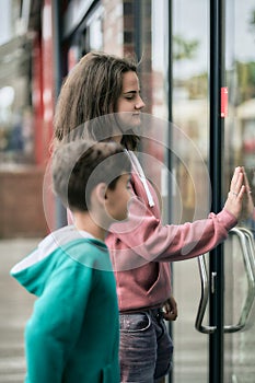 Boy and girl shows their hands on a shop window and wishes a present.