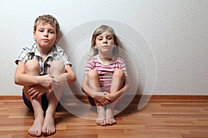 Boy and girl sit leaning on wall