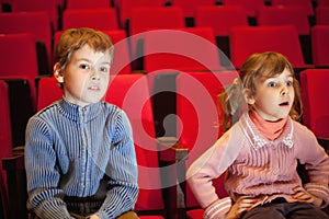 Boy and girl sitting on armchairs at cinema