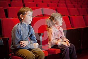 Boy and girl sitting on armchairs at cinema