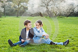 Boy and girl sitting on green meadow