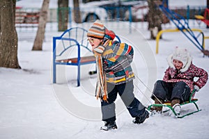 Boy and girl sledding in the snowy yard. Winter background