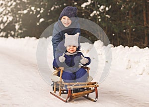 Boy and a girl sledge in winter in nature. Brother and sister together