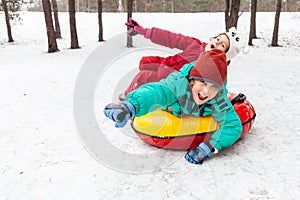 Boy and girl sliding on snow tubing