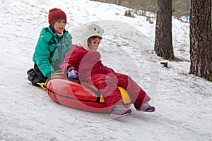 Boy and girl sliding on snow tubing