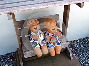 little boy and girl smiling and laughing happily while sitting in wooden chair arch on gravel floor