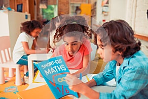 Boy and a girl solving math problems with a textbook