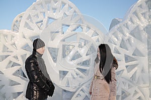 Boy and girl stand near ice wall with triangular holes