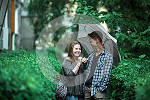 Boy and girl standing under an umbrella on the street.