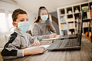 Boy and girl studies at home, wear protective masks, and doing school homework.