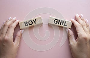 Boy or Girl symbol. Concept word Boy or Girl on wooden blocks. Man hand. Beautiful pink background. Gender and Boy or Girl concept