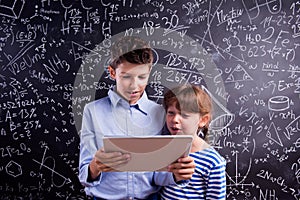 Boy and girl with tablet against big blackboard, school
