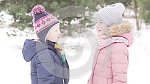 A boy and a girl talk on a walk in the snowy forest