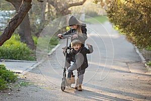 A boy and a girl are trying to ride together on a scooter