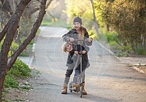 A boy and a girl are trying to ride together on a scooter