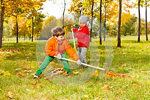 Boy and girl with two rakes working cleaning grass